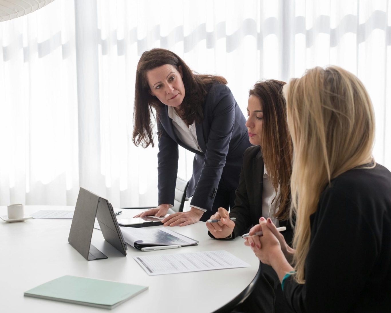 les fondamentaux du développement en réseau Trois femmes en réunion, discutant autour d'une table avec un ordinateur portable.