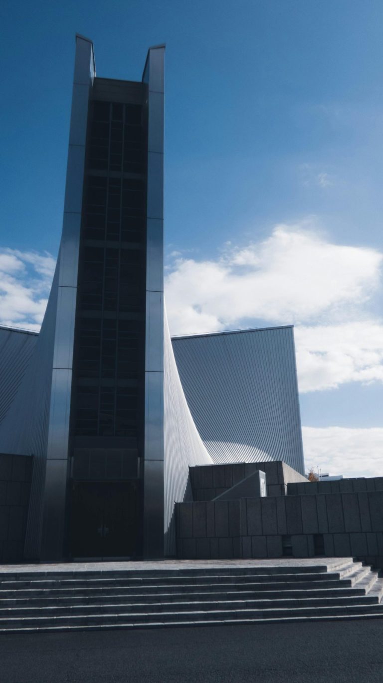Edifice moderne Édifice moderne avec une grande structure verticale et des lignes géométriques sous un ciel bleu.